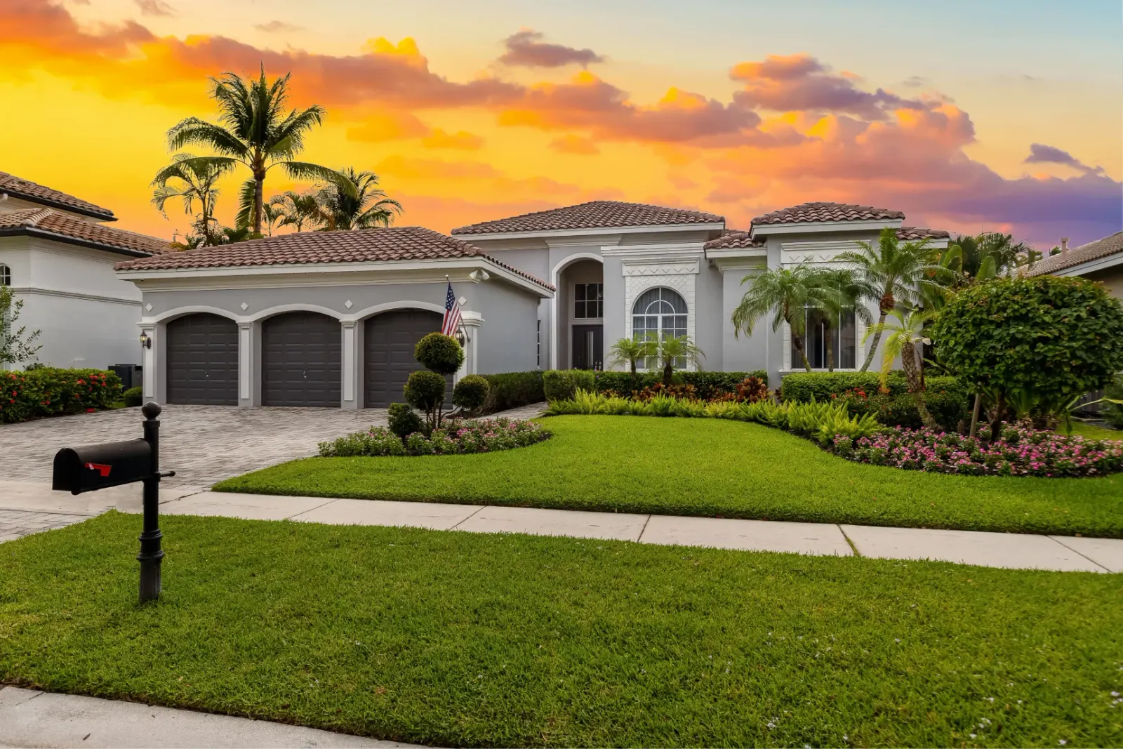 Luxury single-story home with manicured lawn and a three-car garage at sunset.