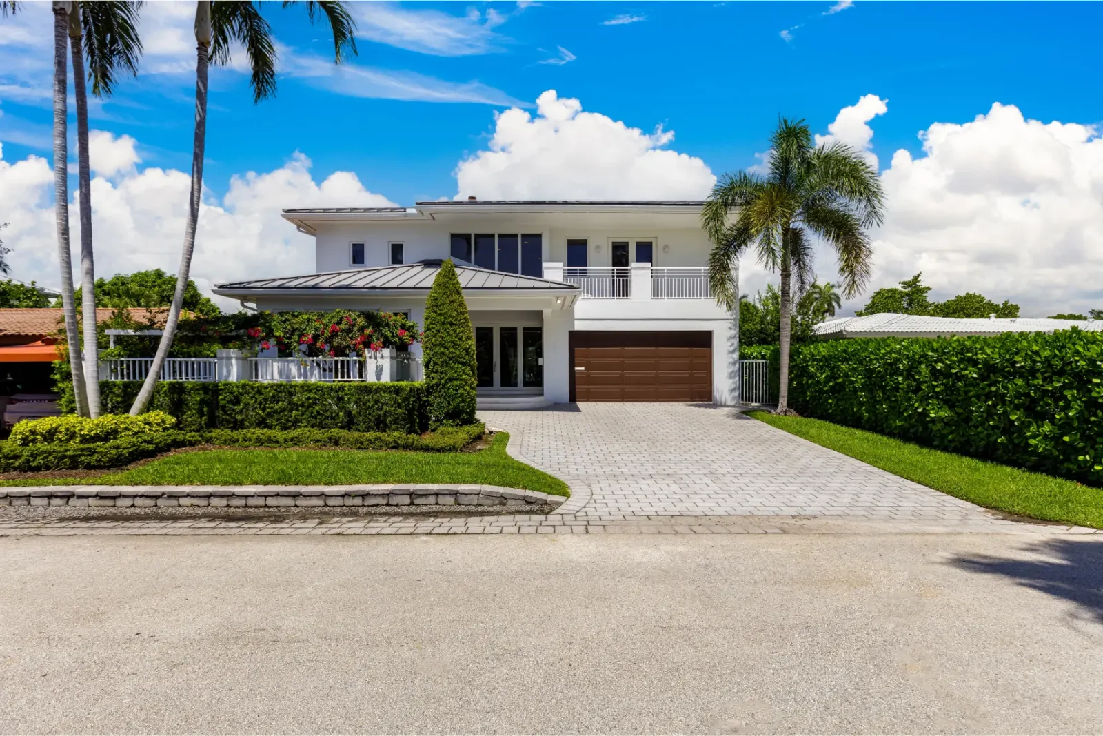 Modern white two-story home with palm trees and a landscaped yard.
